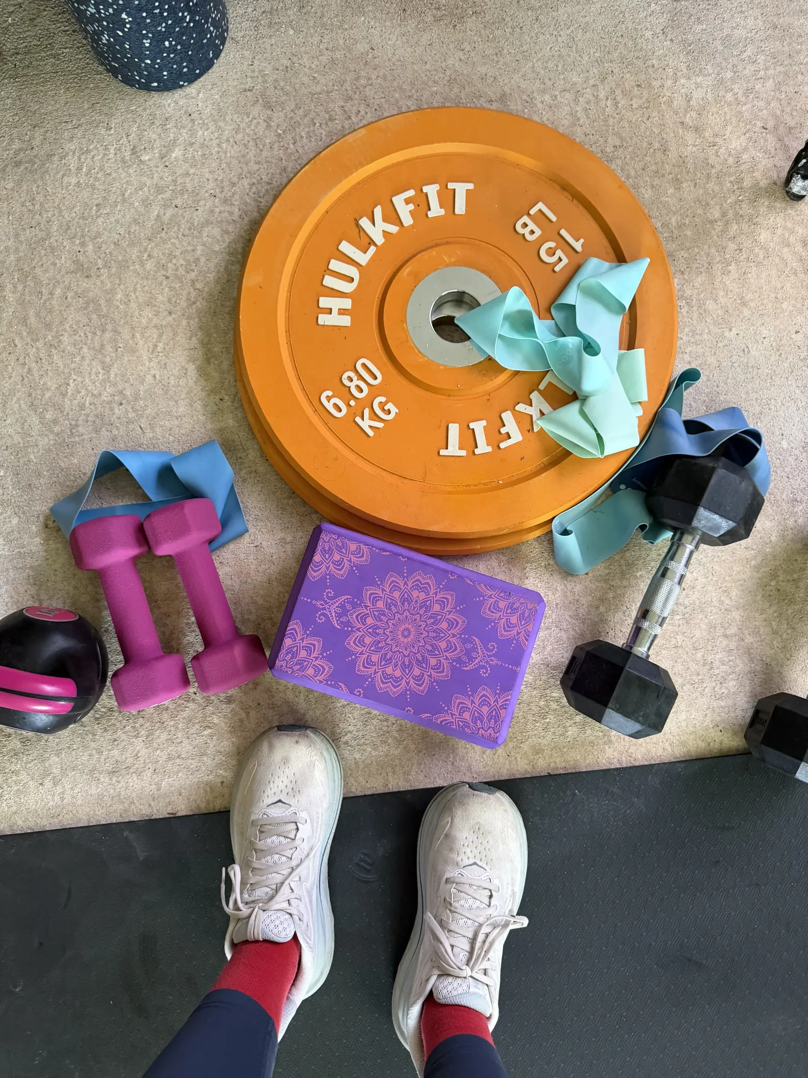 Weights, resistance bands, and running shoes set out for a workout